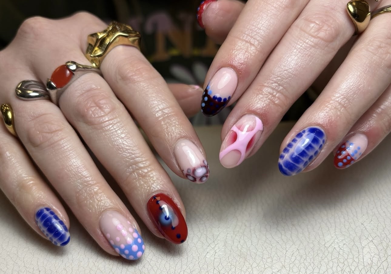 Nail art in blauw, rood en roze, met gouden en zilveren ringen